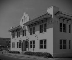 A historic building with a decorative facade, featuring multiple windows and a curved entrance. The structure is painted white and has a unique architectural design.