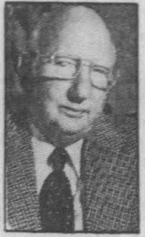 A black and white portrait of Raymond Harper, a distinguished man wearing glasses and a checkered blazer.