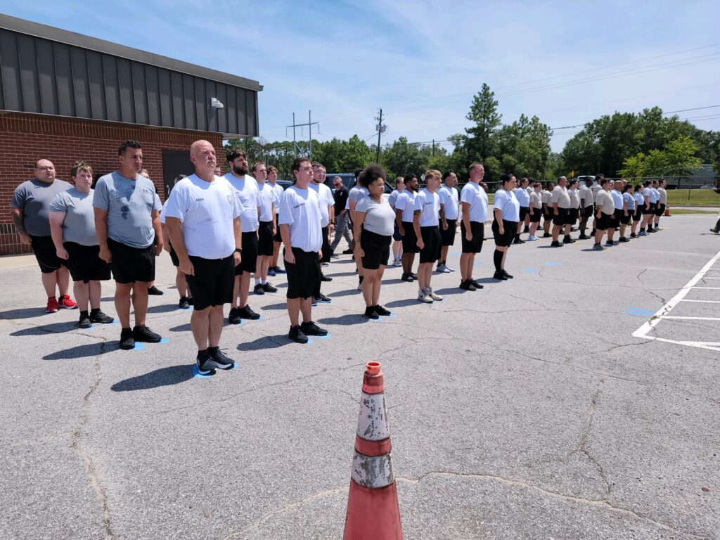 Group of law enforcement academy trainees standing in formation outside the George Stone Criminal Justice Training Center.