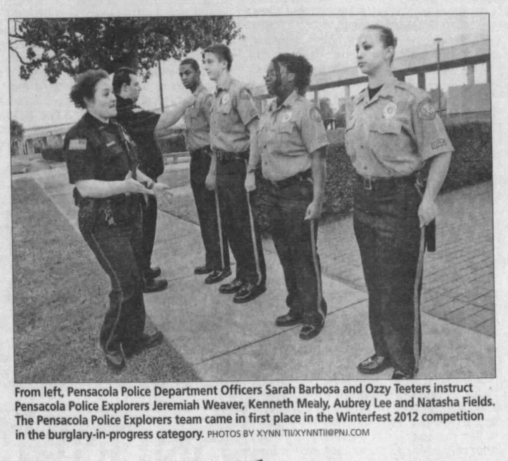 A Pensacola Police Department officer instructs five members of the Pensacola Police Explorers team, who are dressed in uniforms. The team recently won first place in the Winterfest 2012 competition for burglary-in-progress.