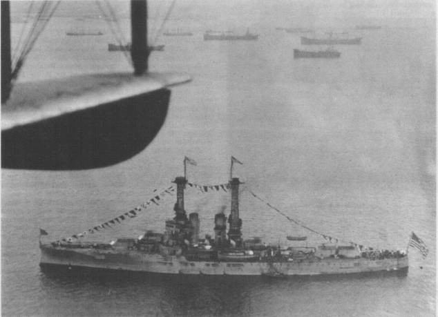 Aerial view of the USS Florida battleship in the water, decorated with flags and surrounded by smaller ships.