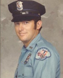 Portrait of a police officer in uniform, smiling at the camera.