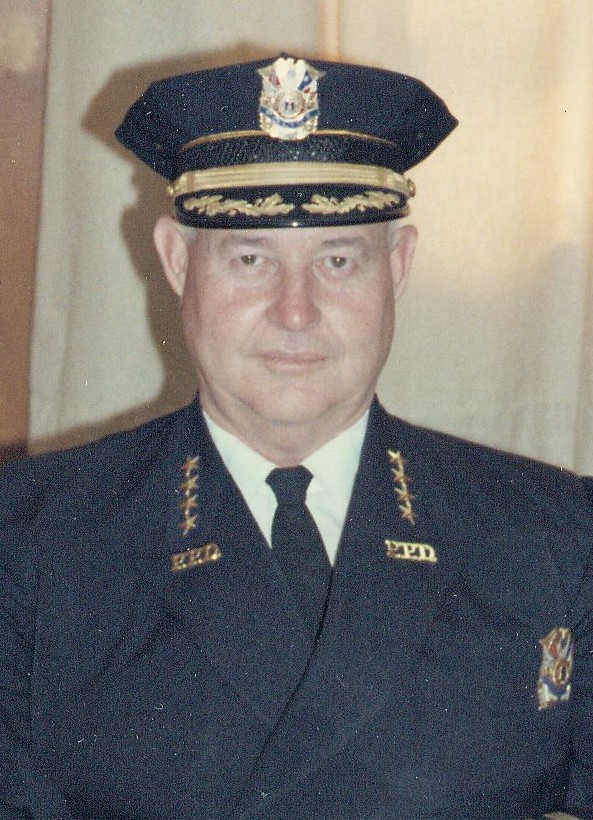 Portrait of a police chief in uniform with a formal hat, featuring insignia and epaulettes.
