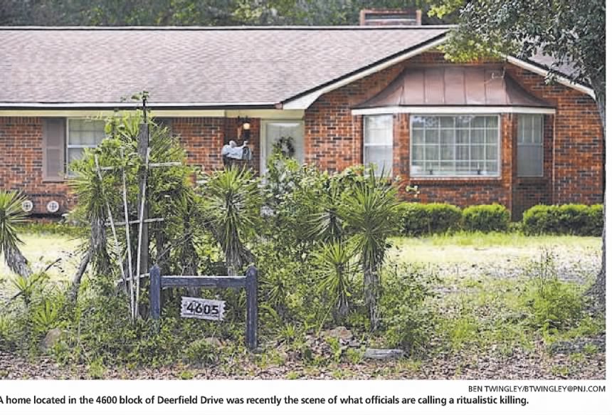 A brick home with a front yard overgrown with bushes and plants, featuring a house number sign reading '4605'.