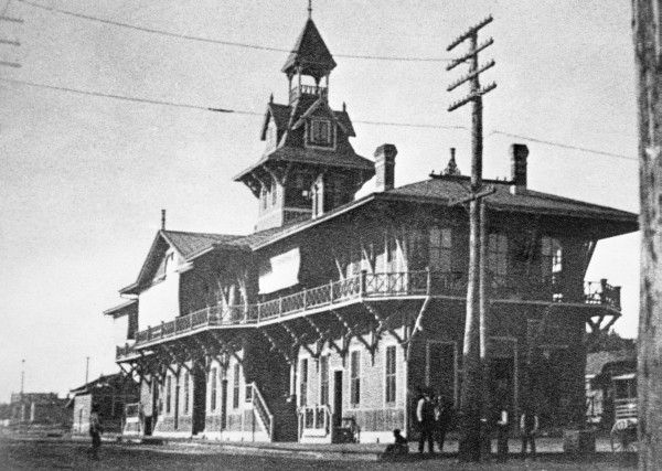 Historic train station with a peaked roof and decorative architecture, featuring a balcony and wooden detailing.