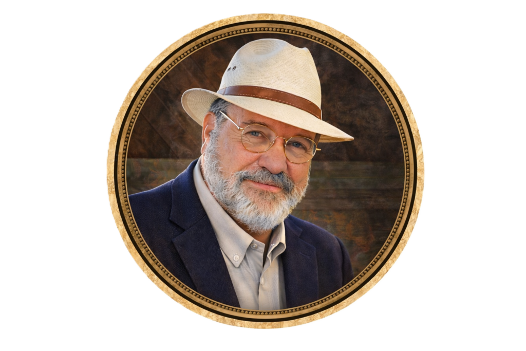 A well-dressed man with glasses and a straw hat, smiling pleasantly. He has a gray beard and is wearing a blue blazer over a light shirt. The image is framed in a round, decorative border.