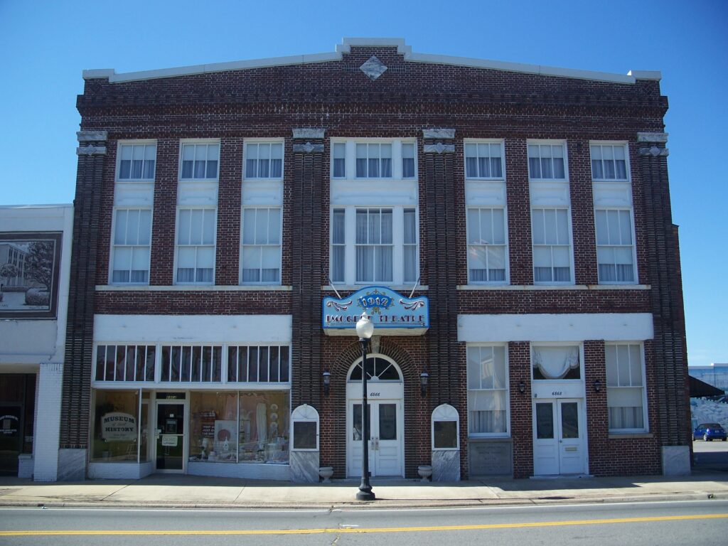 Historic brick building featuring a vintage theater facade with large windows and a decorative marquee sign.