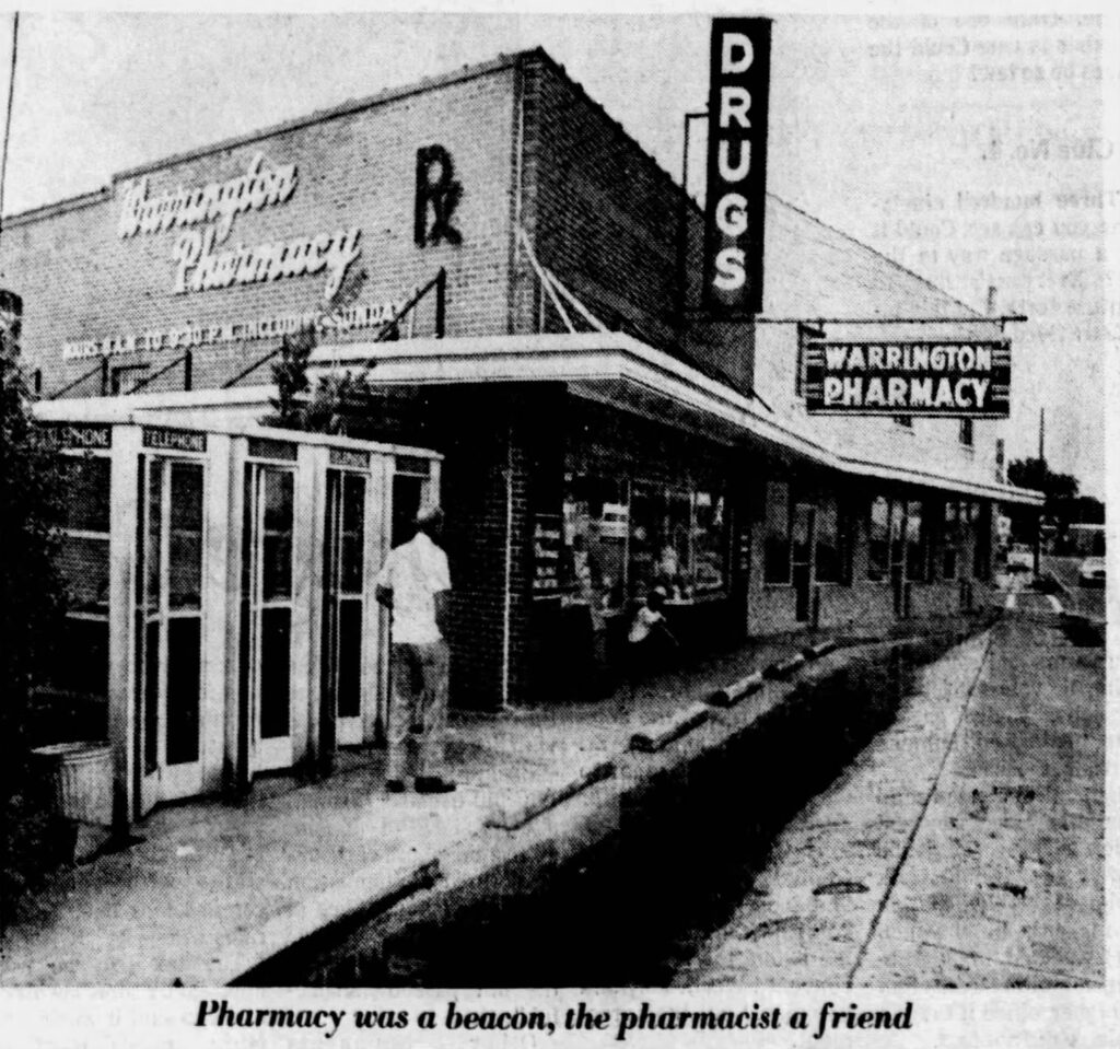 A vintage photograph of a pharmacy storefront with a sign reading 'DRUGS' and 'Warrington Pharmacy', featuring telephone booths outside and a person standing nearby.
