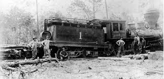 Historic black and white image of a steam locomotive with six men posing alongside it in a wooded area.